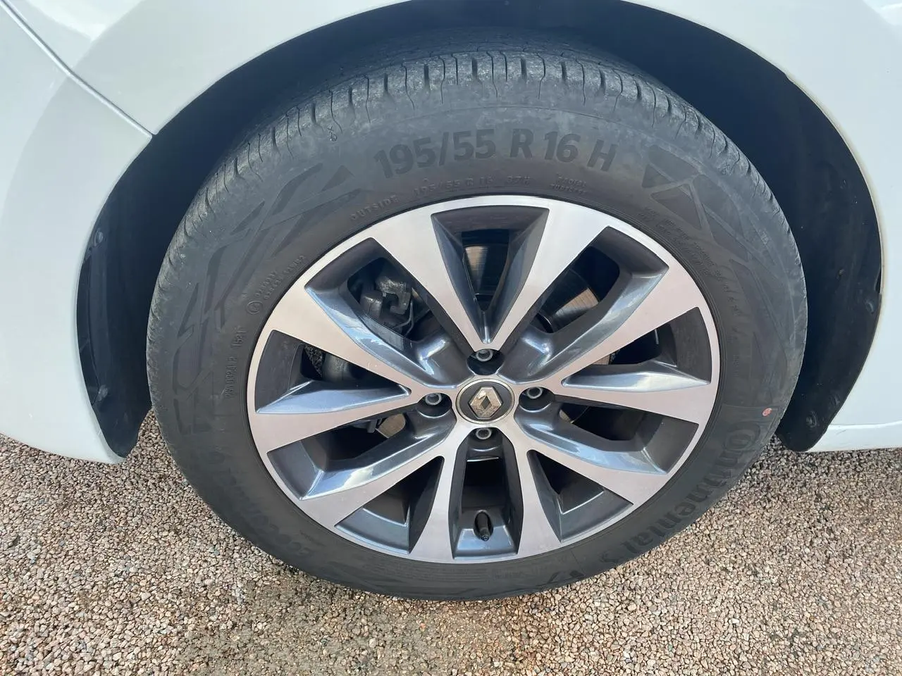 Gros plan sur la roue avant gauche d'une Renault Clio blanche avec jante alliage à dix branches.