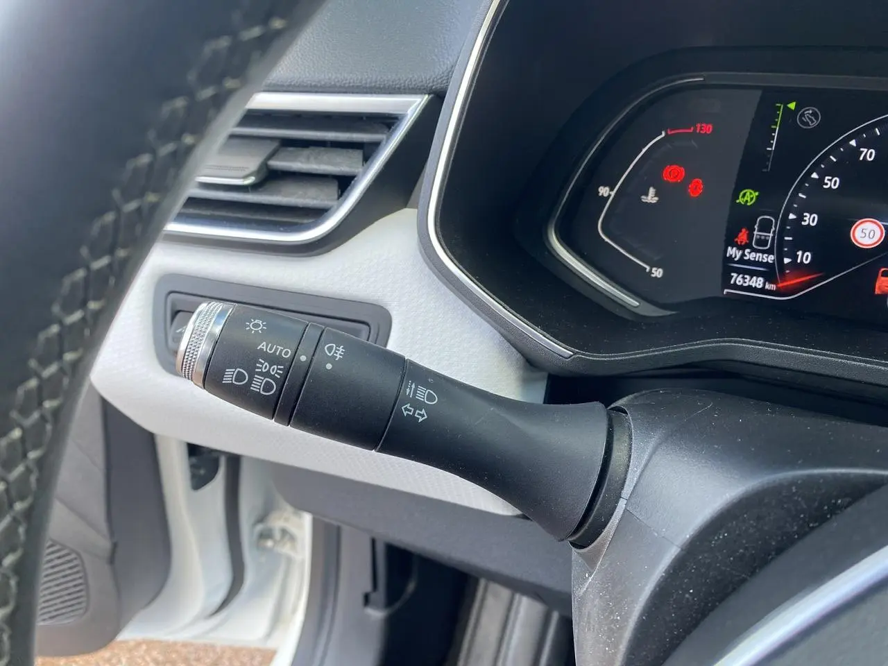 Gros plan sur la commande des phares et clignotants à gauche du volant dans une Renault Clio blanche de 2021.