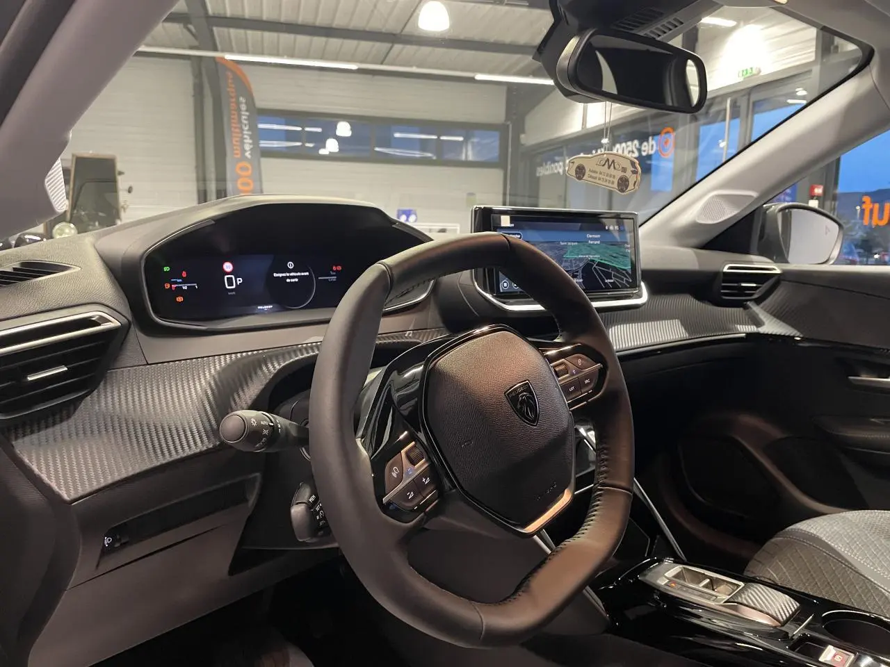 Intérieur Peugeot 208 2025 vue du poste de conduite, volant compact cuir et tableau de bord numérique avec écran tactile.