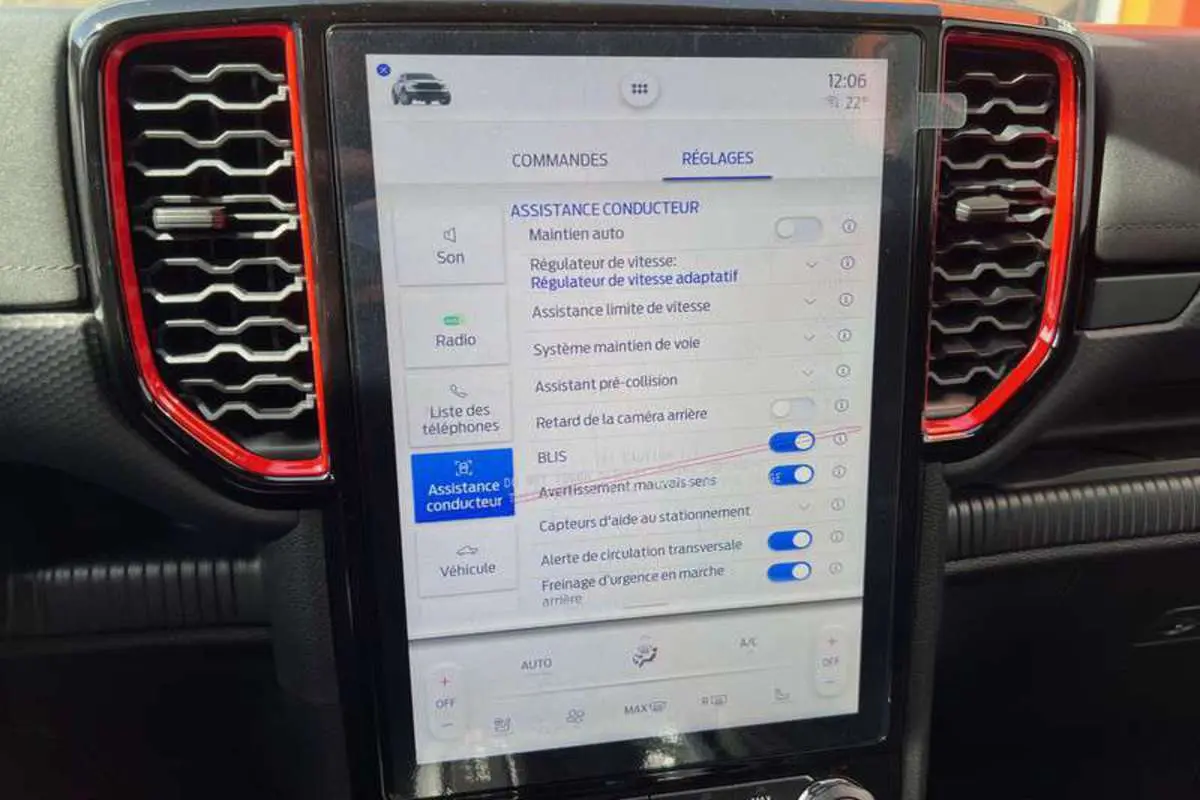 Écran tactile central du Ford Ranger Raptor 2025 avec réglages d'assistance conducteur, entouré de grilles d'aération rouges.