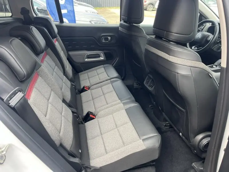 Vue intérieure côté droit sur les sièges arrière gris et noirs du Citroën C5 Aircross Blanc Banquise avec détails rouges et cuir.