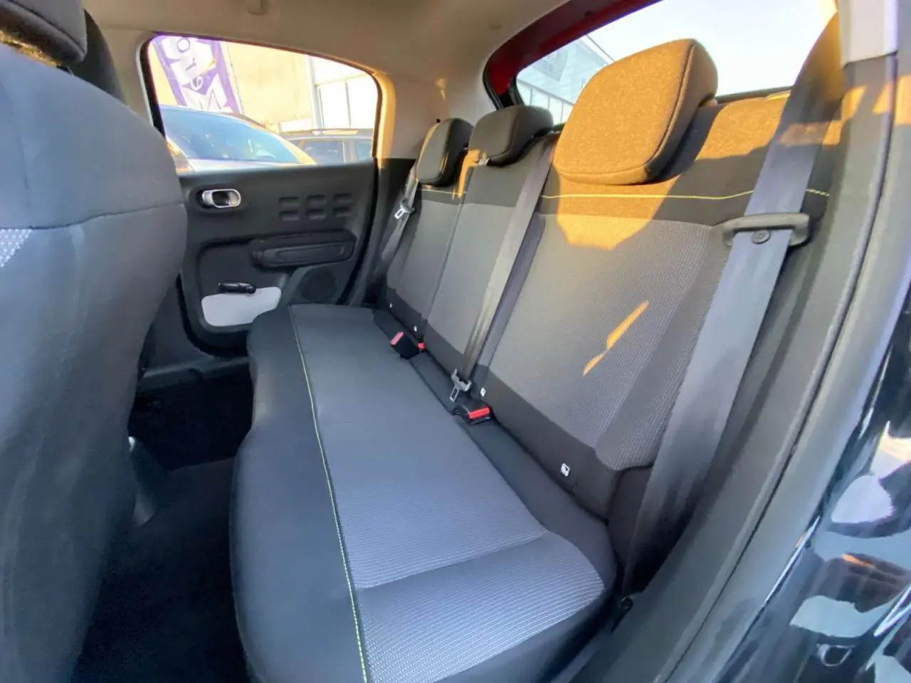 Banquette arrière en tissu gris avec surpiqûres jaunes, vue côté gauche de la Citroën C3 Shine 2023 noir toit rouge.