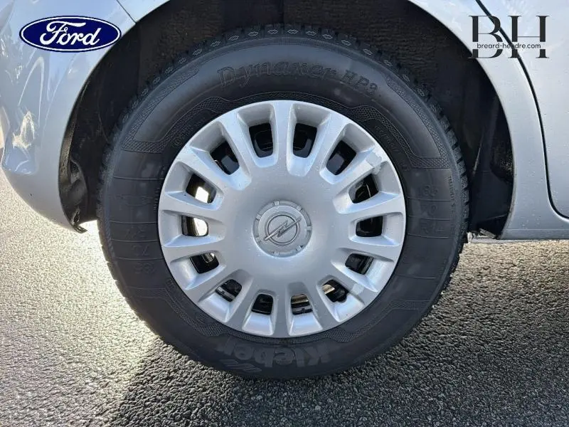 Gros plan sur la roue avant gauche d'une Opel Corsa gris minéral avec enjoliveur à 12 ouvertures.