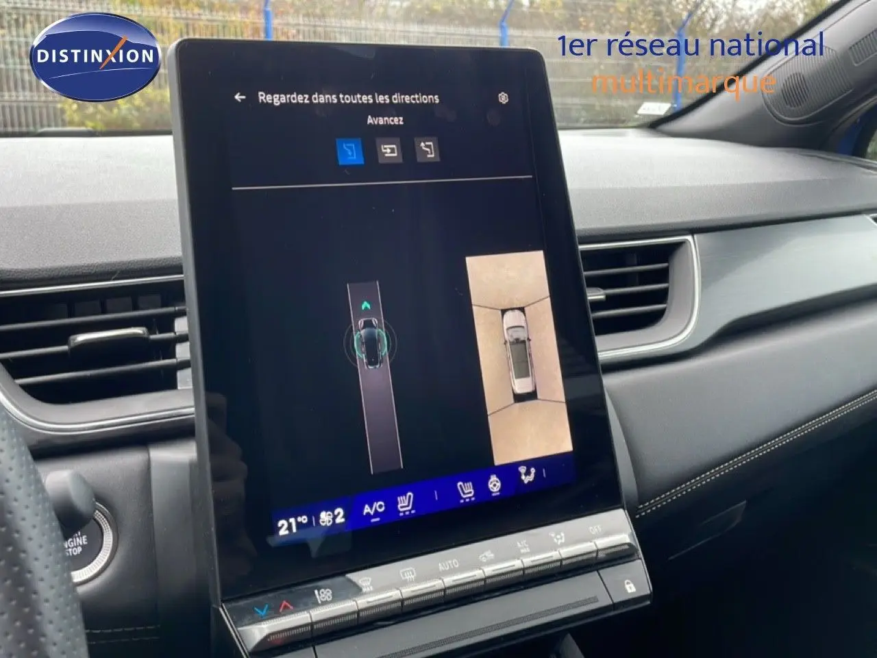 Vue intérieure centrée sur l'écran tactile du tableau de bord du Renault Symbioz bleu Iron Metal, affichant la caméra 360° et l'aide au stationnement.