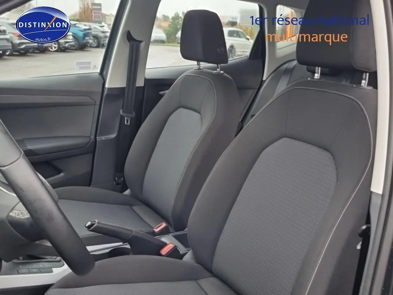 Vue intérieure côté avant droit montrant les sièges tissu gris et le levier de frein à main d'une SEAT Arona 2025.