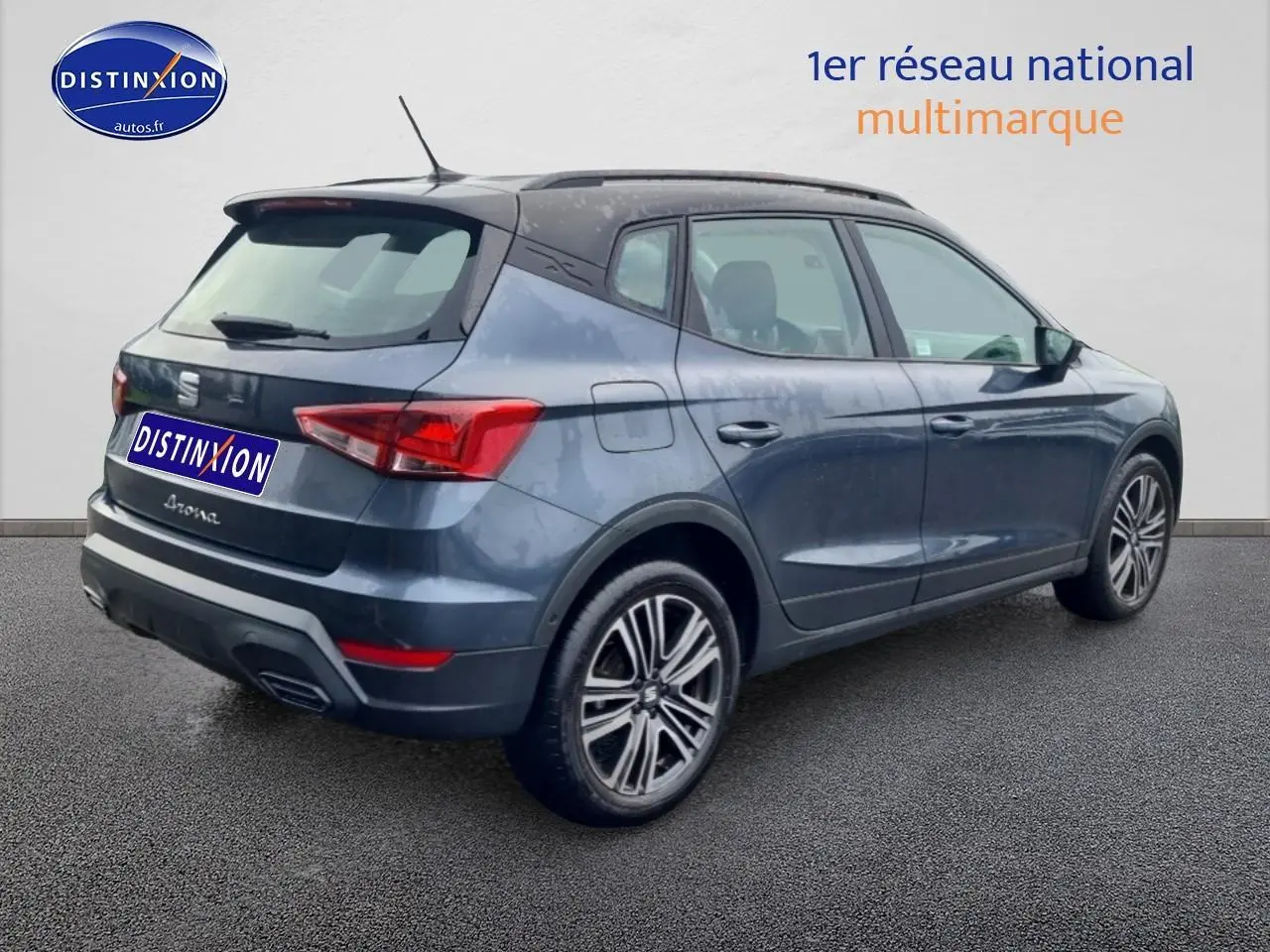 Vue 3/4 arrière droite d'une SEAT Arona gris magnétique avec jantes 17 pouces et barres de toit visibles.