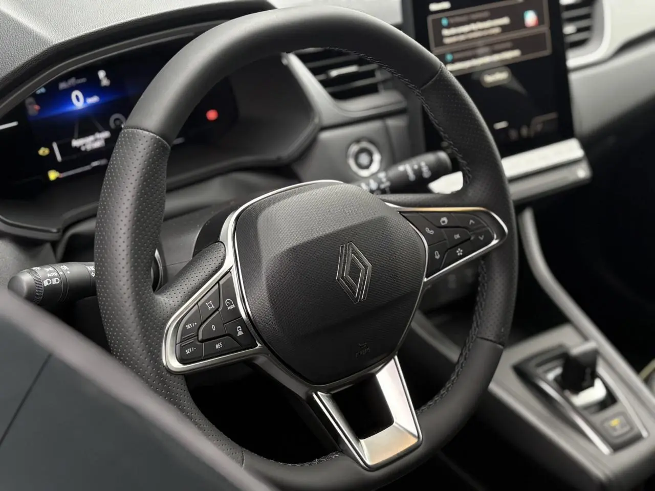 Vue rapprochée du volant noir perforé du Renault Captur 2025 avec commandes intégrées et tableau de bord numérique.