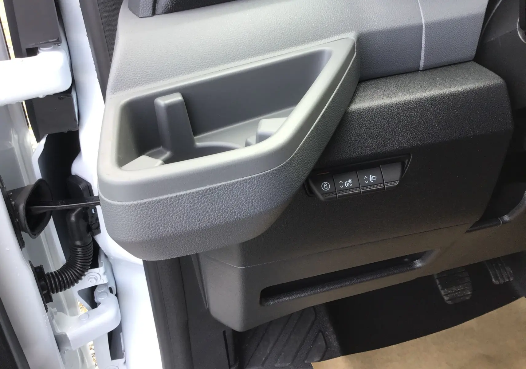 Gros plan sur la porte côté conducteur du Renault Master blanc 2025, montrant la poignée intérieure et les boutons de réglage des phares.