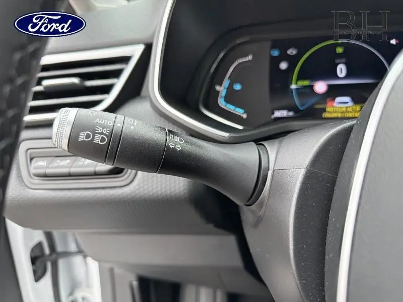 Gros plan sur la commande des phares et clignotants à gauche du volant dans l'habitacle d'une Renault Clio blanche.