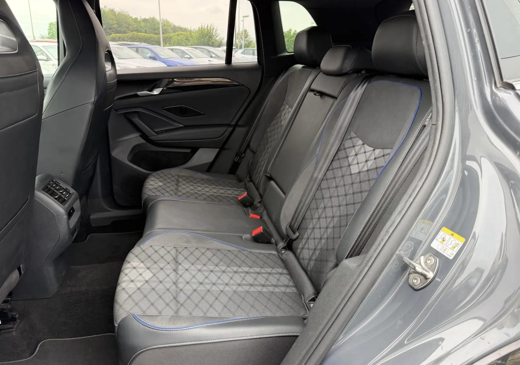 Vue côté droit de l'intérieur arrière du Volkswagen Tiguan gris, avec sièges en tissu et cuir à surpiqûres bleues.