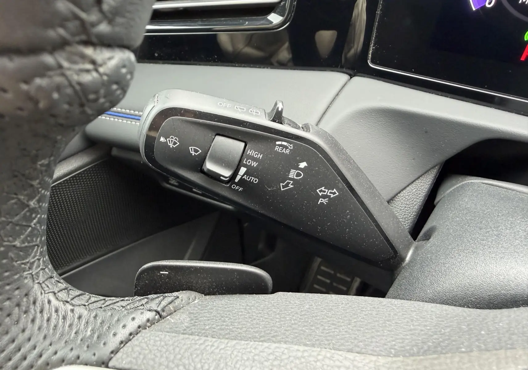 Gros plan sur la commande des essuie-glaces à gauche du volant cuir du Volkswagen Tiguan gris 2025.