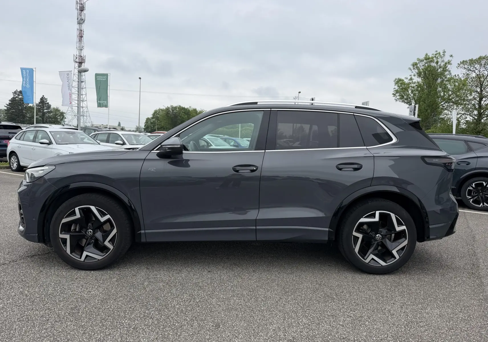 Vue de profil côté gauche d’un Volkswagen Tiguan gris métallisé 2025 avec jantes alliage 19 pouces et vitres teintées.