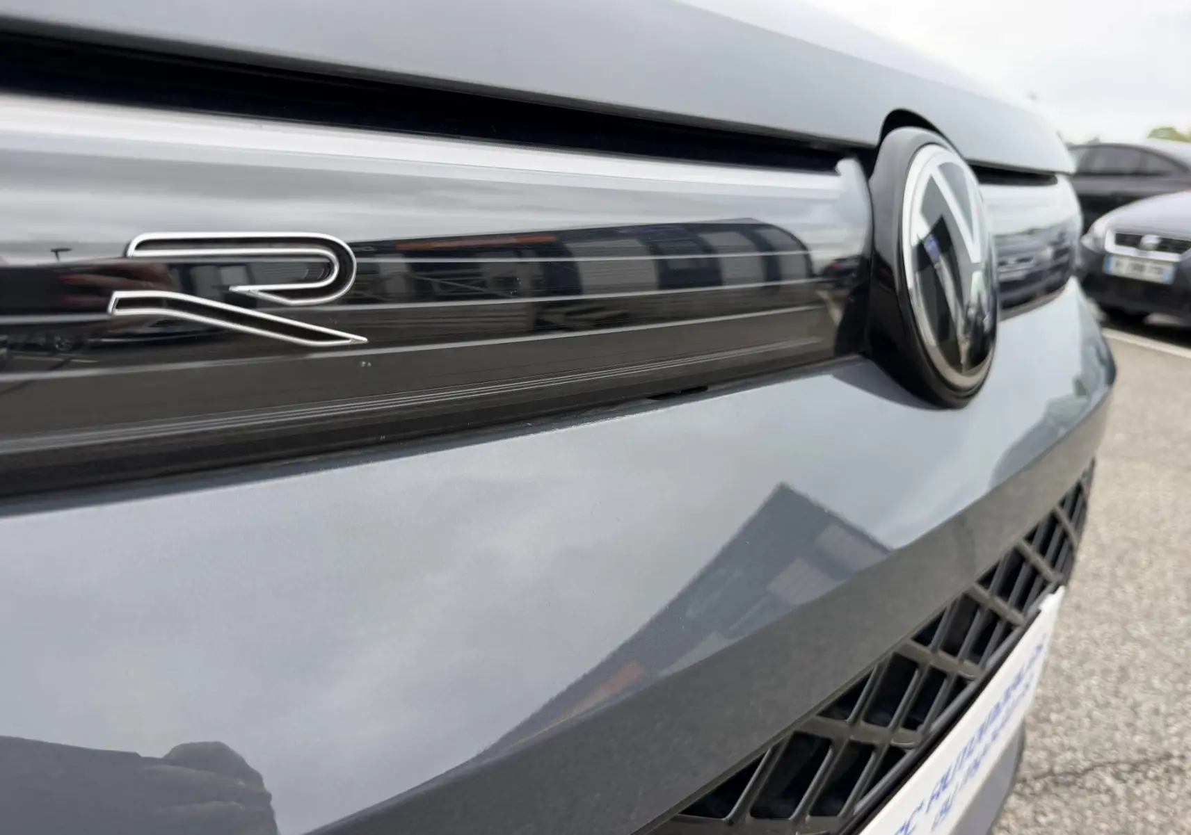 Gros plan sur la calandre avant grise métallisée du Volkswagen Tiguan 2025 avec logo VW et badge R distinctif.