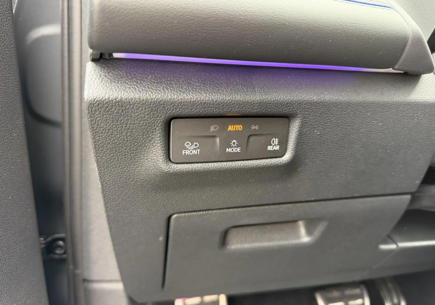 Détail du tableau de bord côté gauche avec commandes d'éclairage et bande lumineuse violette sur Volkswagen Tiguan gris.