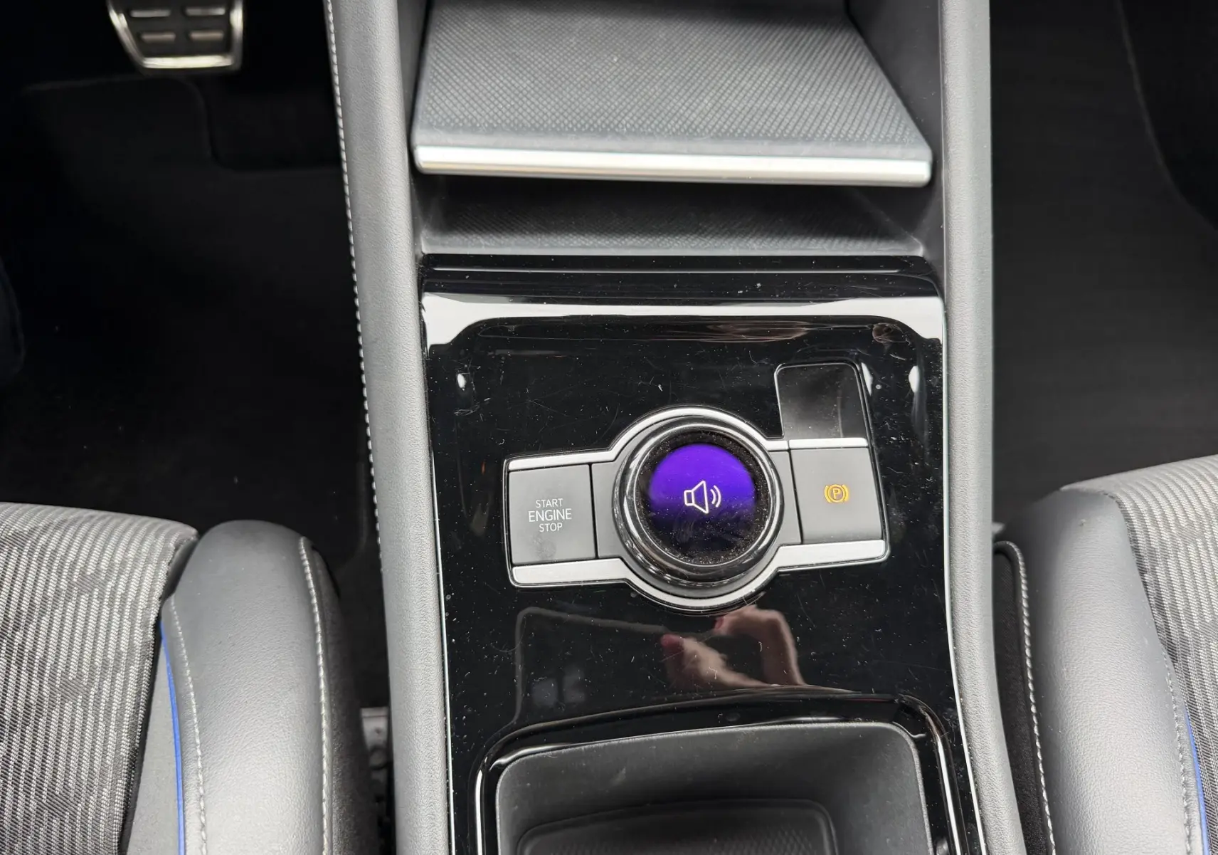 Vue plongeante sur la console centrale noire brillante du Volkswagen Tiguan 2025 avec bouton start/stop et frein à main électronique.