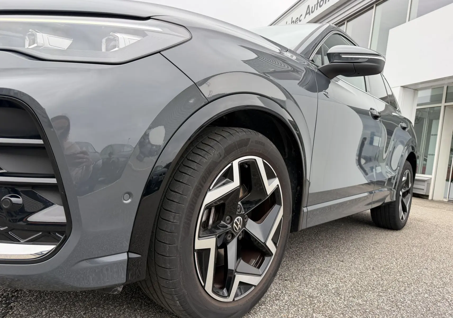 Vue de profil avant droit du Volkswagen Tiguan gris métallisé, mettant en valeur la jante alliage 19 pouces et les projecteurs LED.
