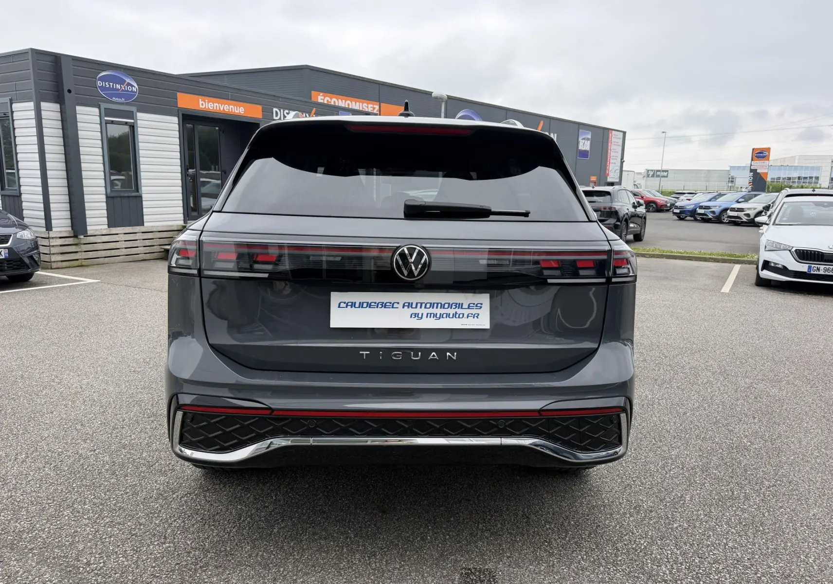 Vue arrière d'un Volkswagen Tiguan gris métallisé avec feux arrière LED et logo VW centré sur un parking extérieur.