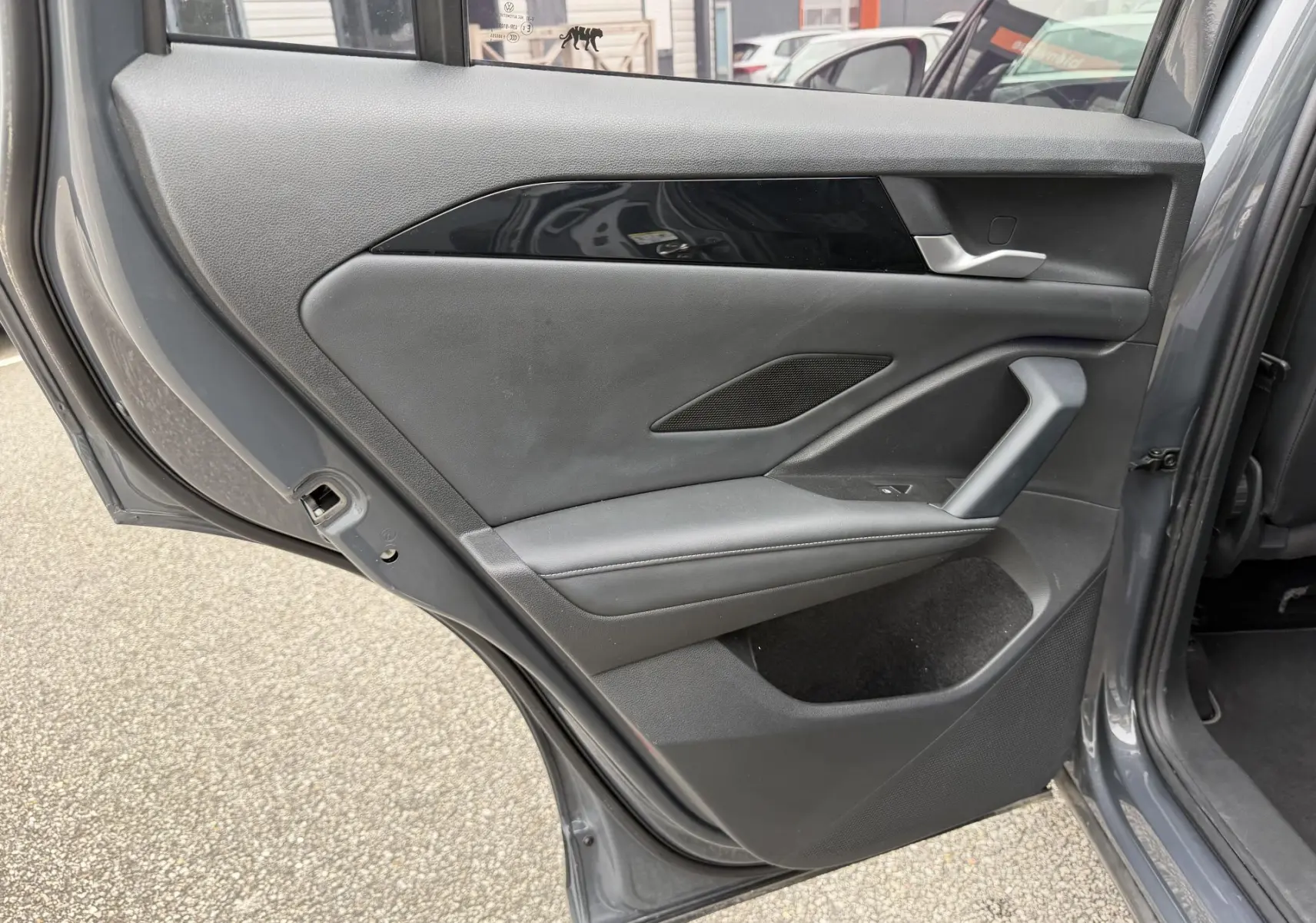 Vue intérieure de la porte arrière gauche grise du Volkswagen Tiguan 2025 avec garniture noire et poignée argentée.