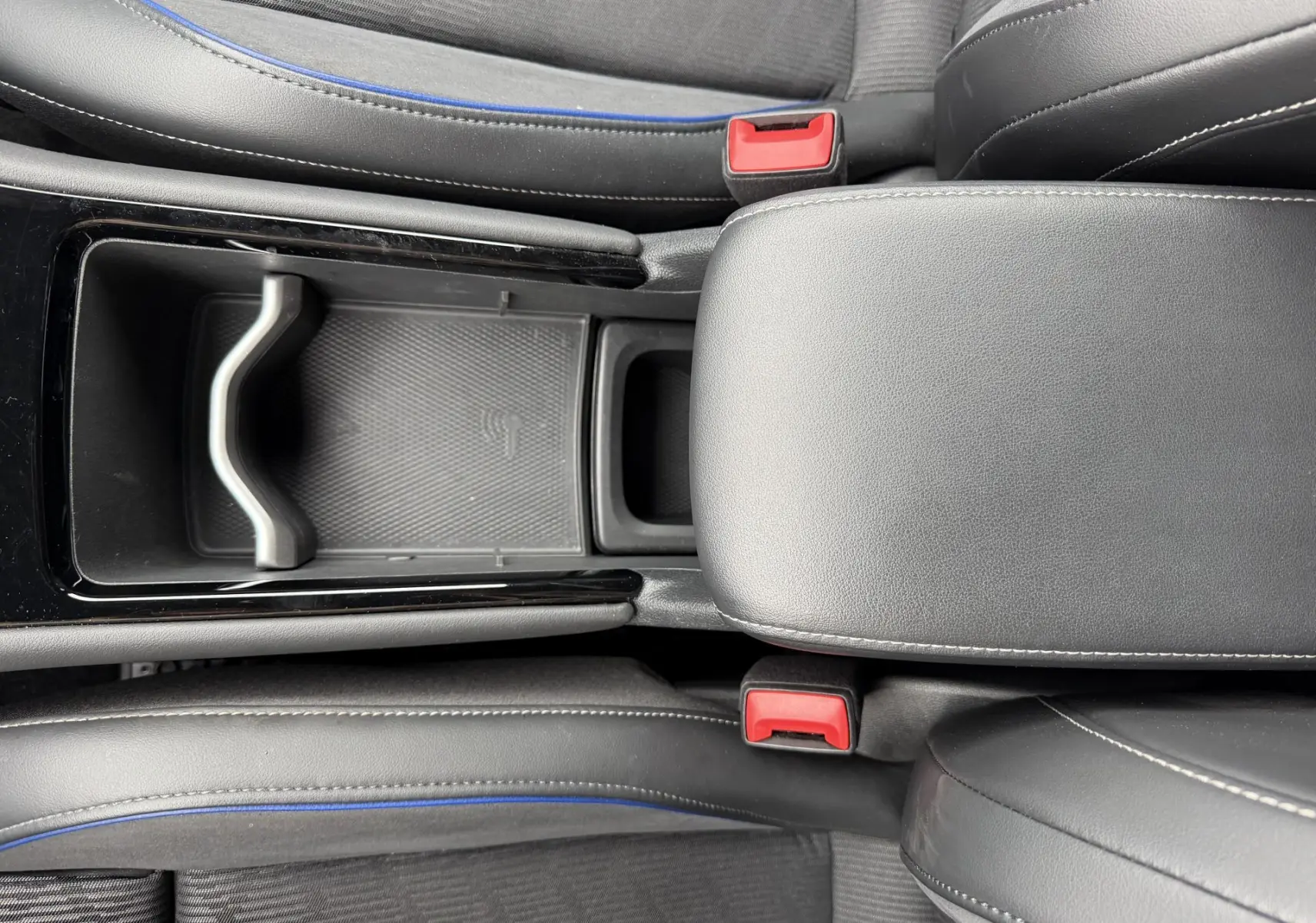 Vue plongeante sur la console centrale en cuir noir avec surpiqûres blanches et sièges gris à surpiqûres bleues du Volkswagen Tiguan 2025.