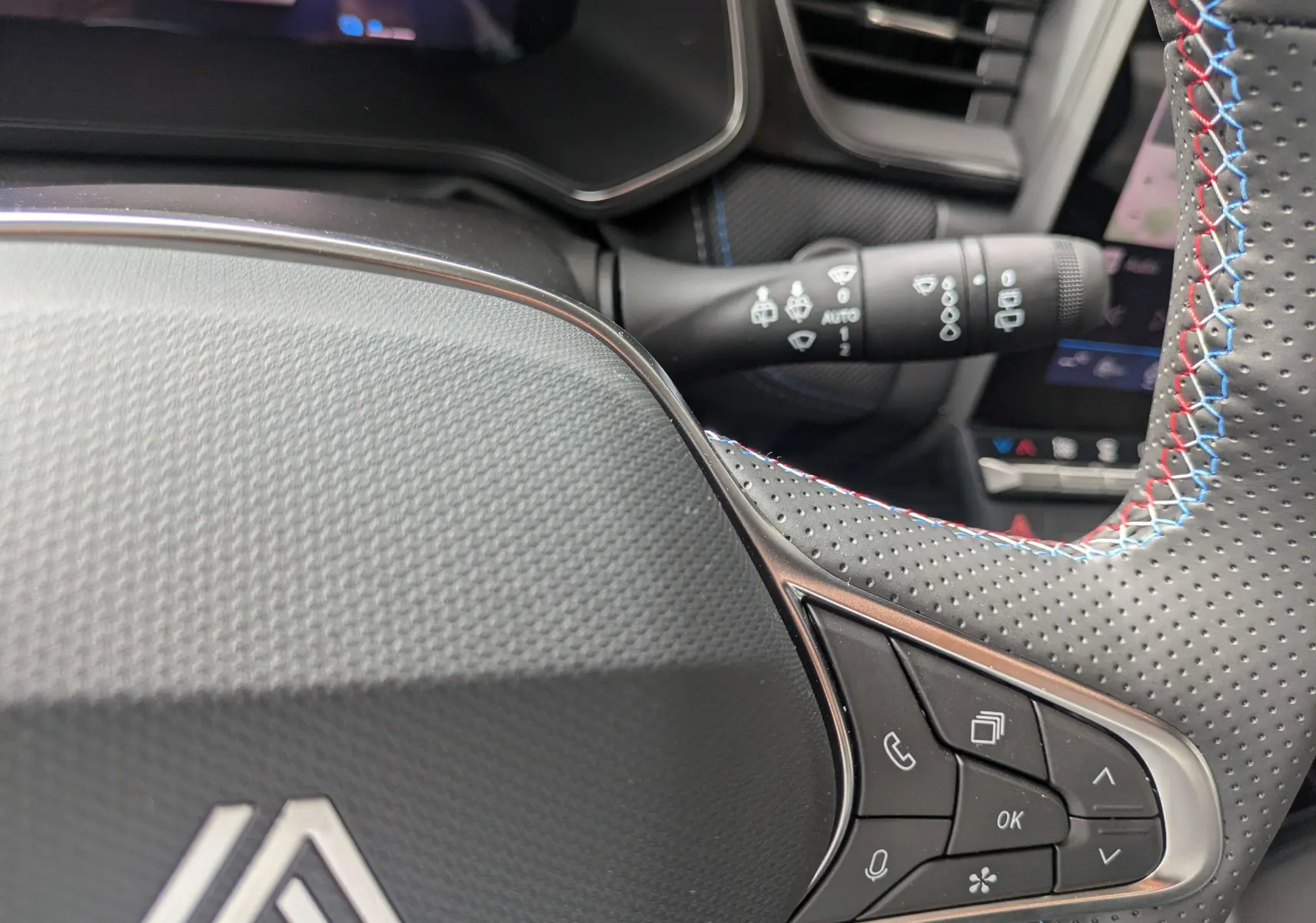 Détail du volant perforé avec surpiqûres tricolores et commandes intégrées, intérieur du Renault Symbioz 2026.