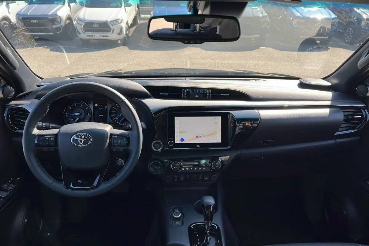 Intérieur du Toyota Hilux 2025 gris atlas, vue frontale du tableau de bord avec écran tactile et volant multifonction.