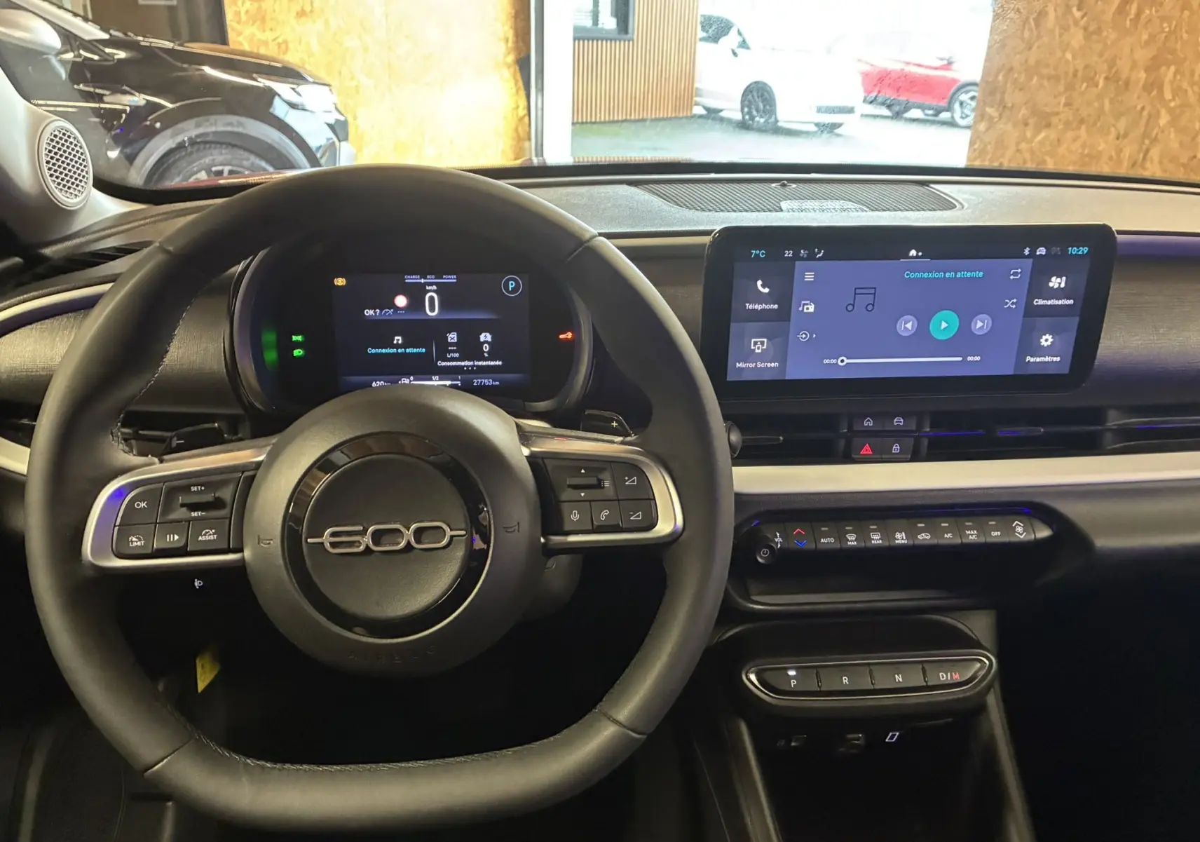 Vue intérieure du tableau de bord de la Fiat 600 1.2 Hybrid 2024 avec volant noir et écran tactile central allumé.