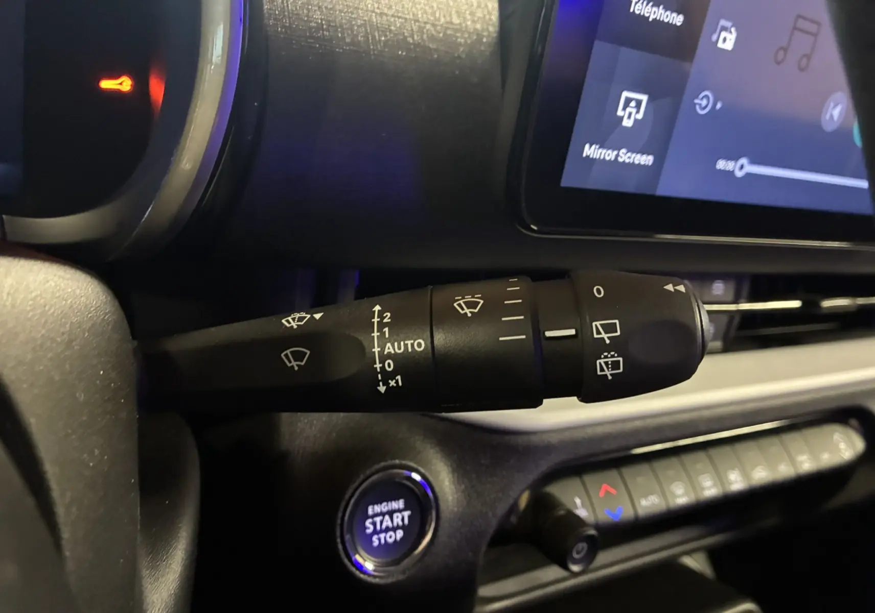 Gros plan sur la commande d’essuie-glace et le bouton start/stop dans l’habitacle noir du Fiat 600 1.2 Hybrid 2024.