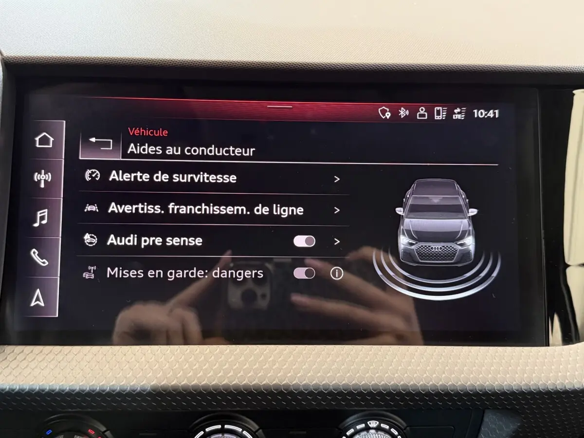 Écran tactile central de l'Audi A1 noir montrant les aides au conducteur avec vue avant du véhicule stylisée.