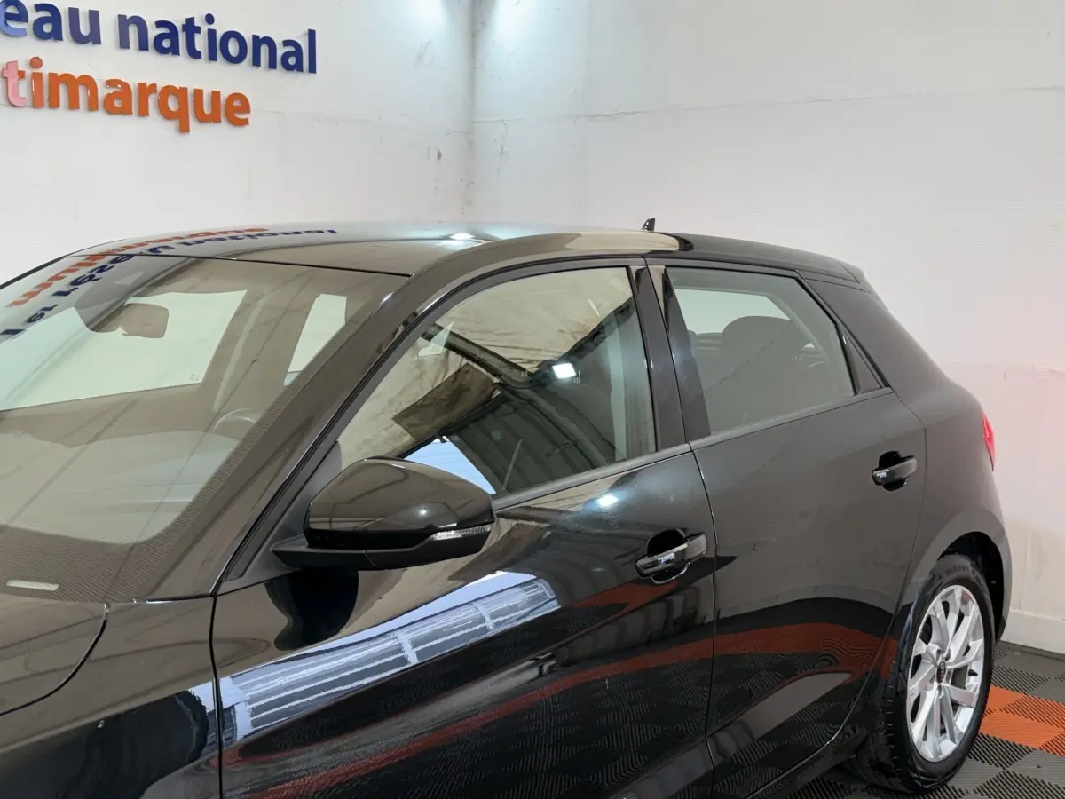 Audi A1 Business Line noire vue de profil côté gauche, avec rétroviseur et poignées de porte visibles.