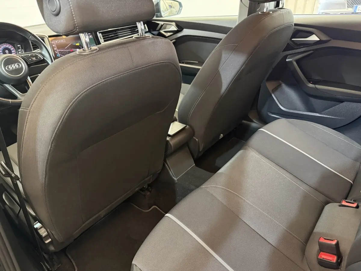 Vue intérieure arrière de l’Audi A1 2021 noire, montrant la banquette tissu et les dossiers des sièges avant.