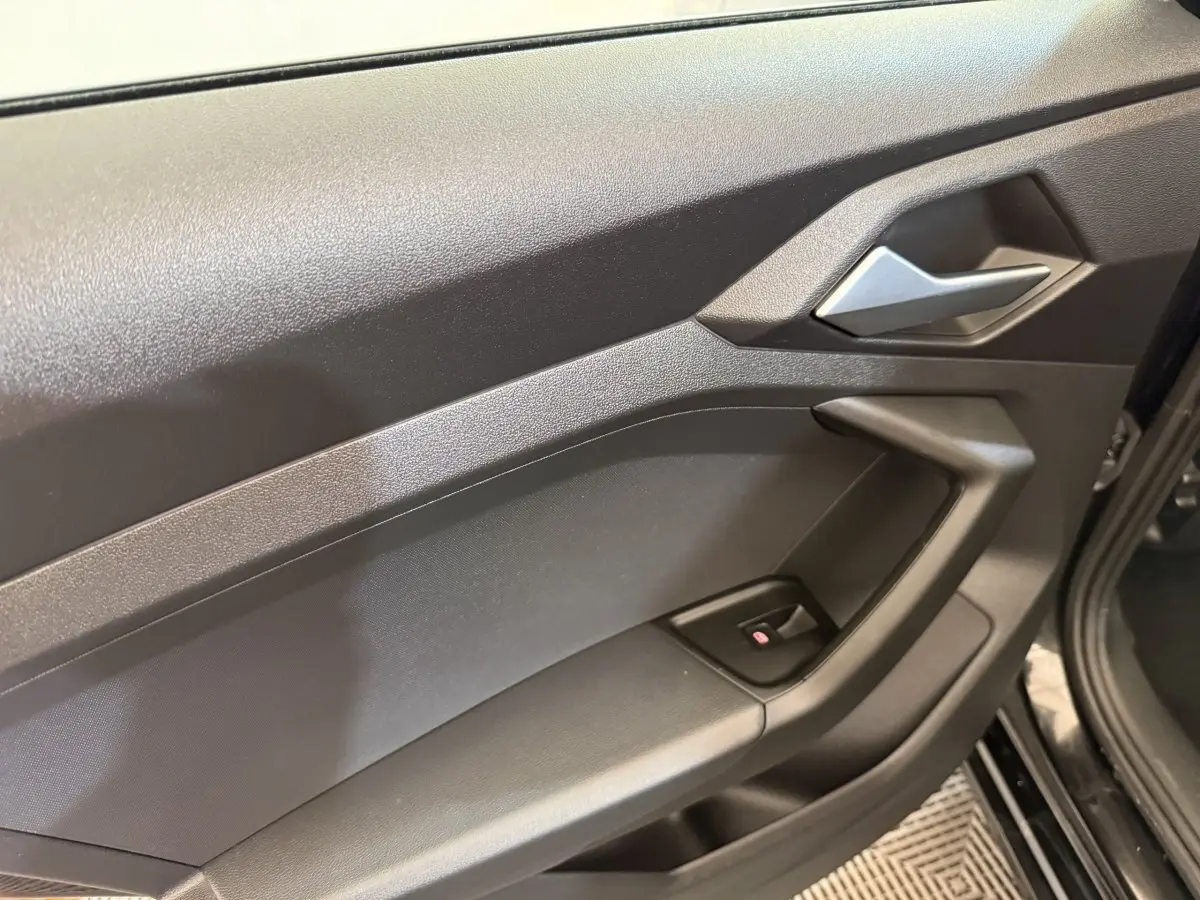 Gros plan sur la porte intérieure côté conducteur noire de l'Audi A1 2021 avec poignée argentée et bouton de lève-vitre.
