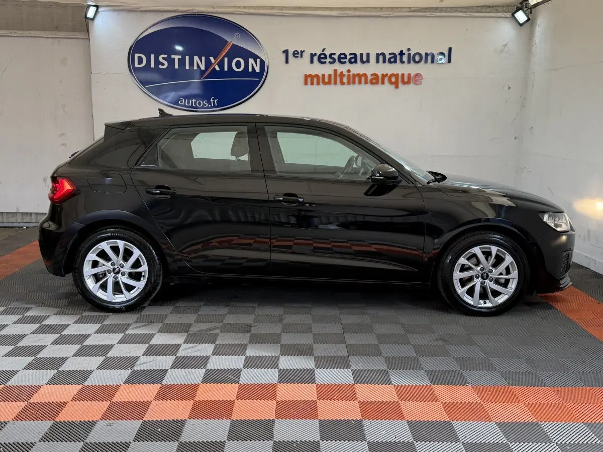 Audi A1 Business Line noire vue de profil côté gauche, avec jantes argentées et feux arrière allumés.