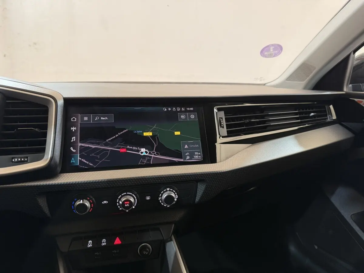 Tableau de bord de l'Audi A1 noir, vue de face sur l'écran tactile de navigation et les commandes de climatisation.