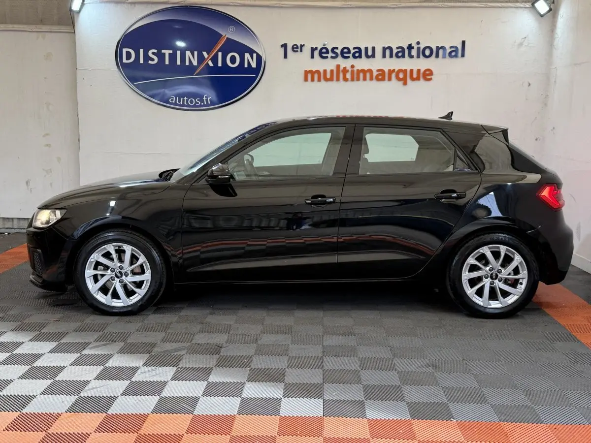 Audi A1 Business Line noire vue de profil côté gauche, avec jantes argentées et feux arrière allumés.