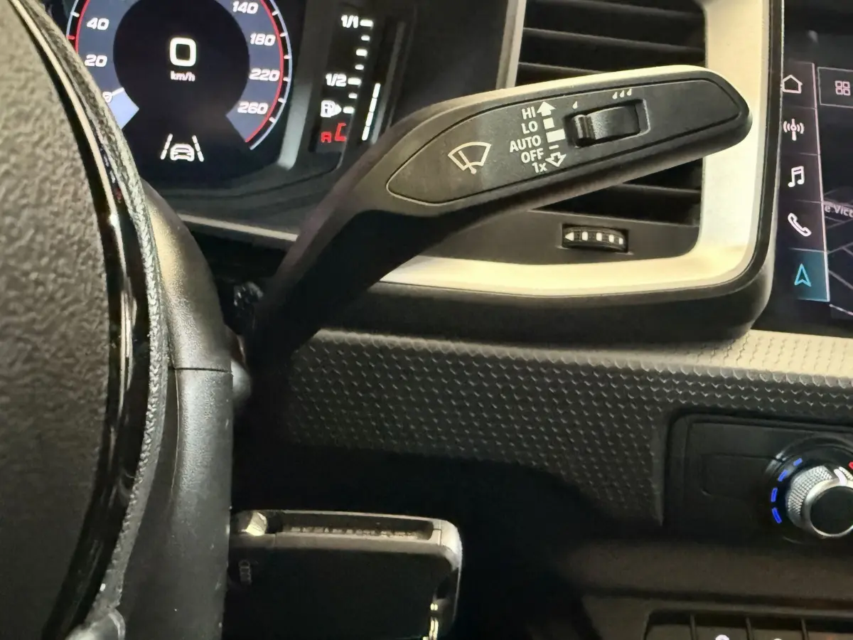 Gros plan sur le commodo d’essuie-glace à gauche du volant cuir noir de l’Audi A1 2021, avec tableau de bord numérique.