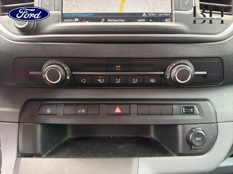 Vue rapprochée de la console centrale du Peugeot Expert Fourgon blanc, montrant les commandes de climatisation et boutons fonctionnels.