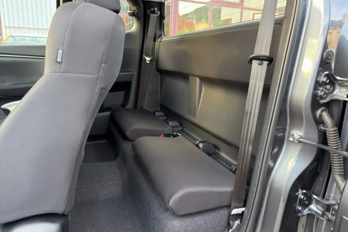 Vue intérieure côté droit sur les sièges arrière strapontins en tissu gris du pick-up Isuzu D-MAX gris Obsidian 2026.