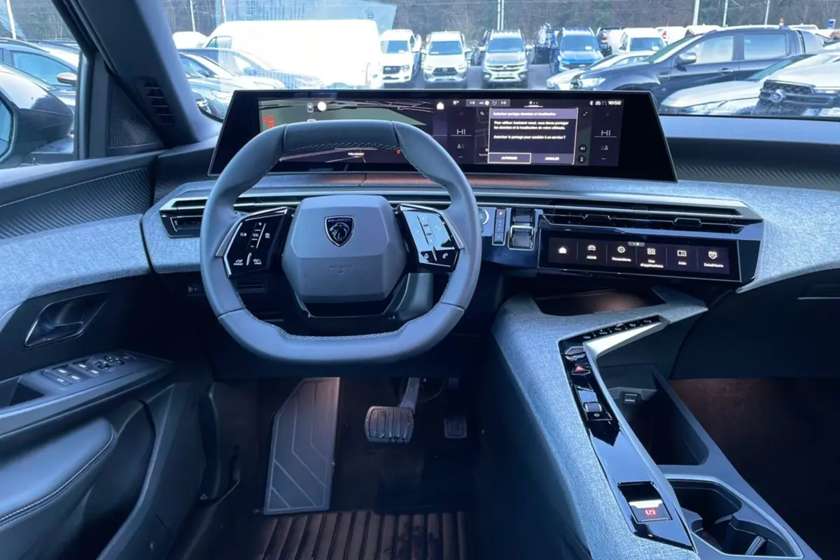Intérieur Peugeot 5008 Hybrid 145 Allure Plus vu de face, volant cuir, écran incurvé 21 pouces et console centrale grise.