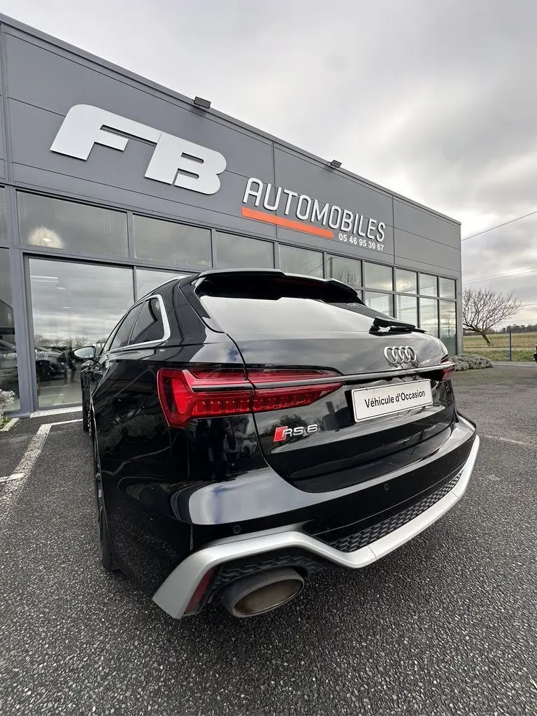 Vue 3/4 arrière droite d'une Audi RS6 Avant noire 2021 avec feux LED et double sortie d'échappement visible.