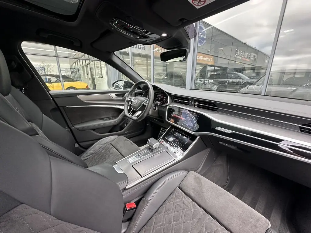 Vue intérieure côté conducteur de l'Audi RS6 Avant 2021 noire, avec tableau de bord digital et finitions cuir et aluminium.