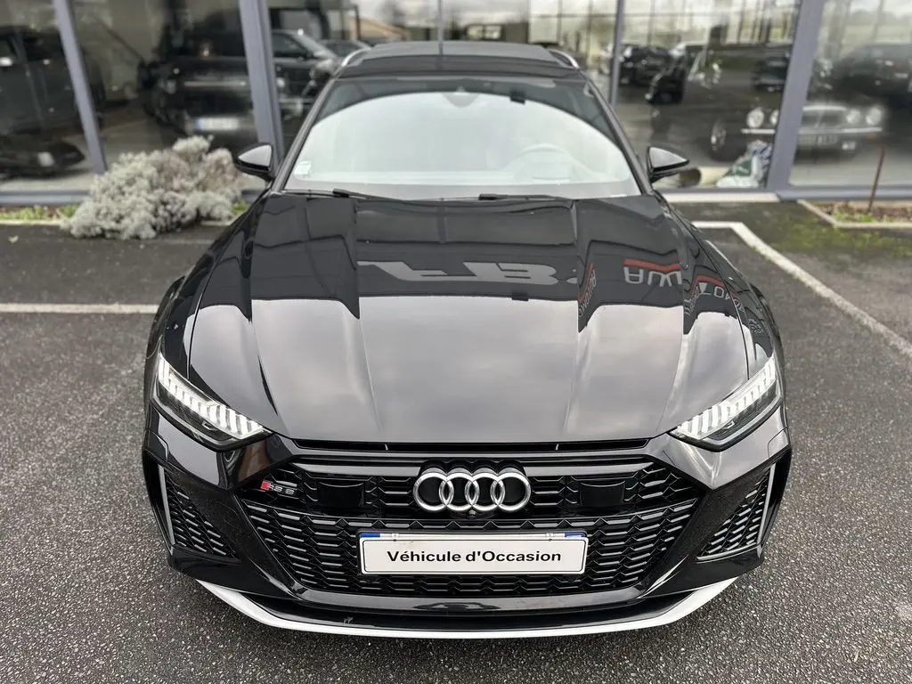 Vue avant d'une Audi RS6 Avant noire 2021 avec calandre noire et phares LED allumés sur parking.