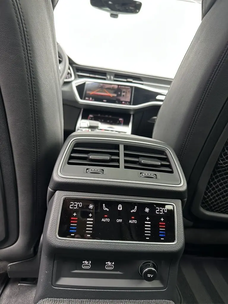 Vue intérieure arrière de l'Audi RS6 Avant 2021 noire, montrant la console de climatisation et les écrans tactiles avant.