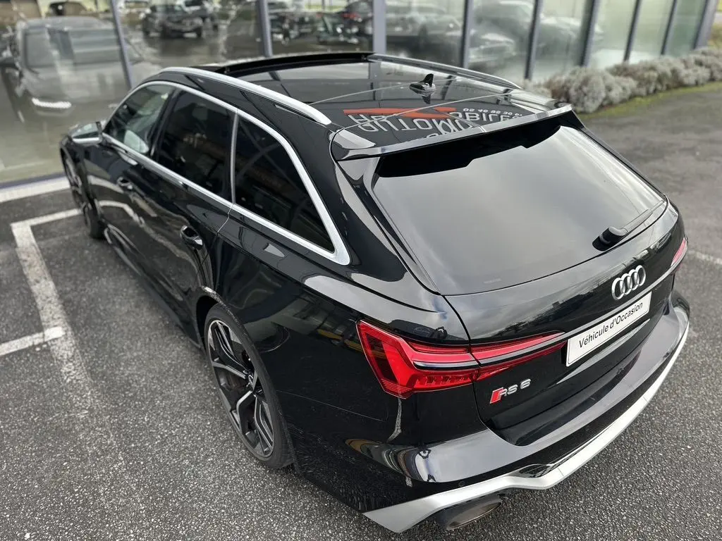Audi RS6 Avant noire vue en 3/4 arrière droit, avec feux arrière LED et toit ouvrant panoramique visible.