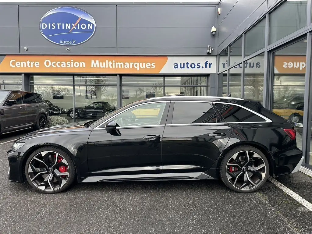 Profil côté gauche d'une Audi RS6 Avant noire 2021 avec grandes jantes alliage et étriers de frein rouges visibles.