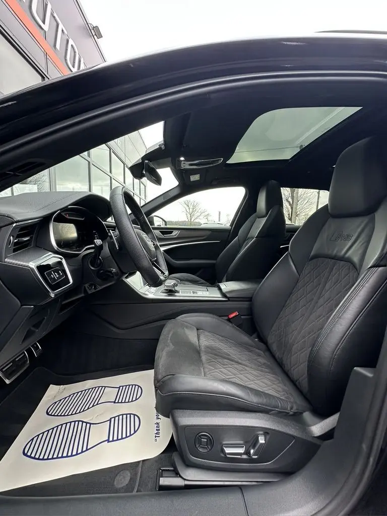 Vue intérieure côté conducteur de l'Audi RS6 Avant 2021 avec sièges en cuir noirs et toit ouvrant panoramique.