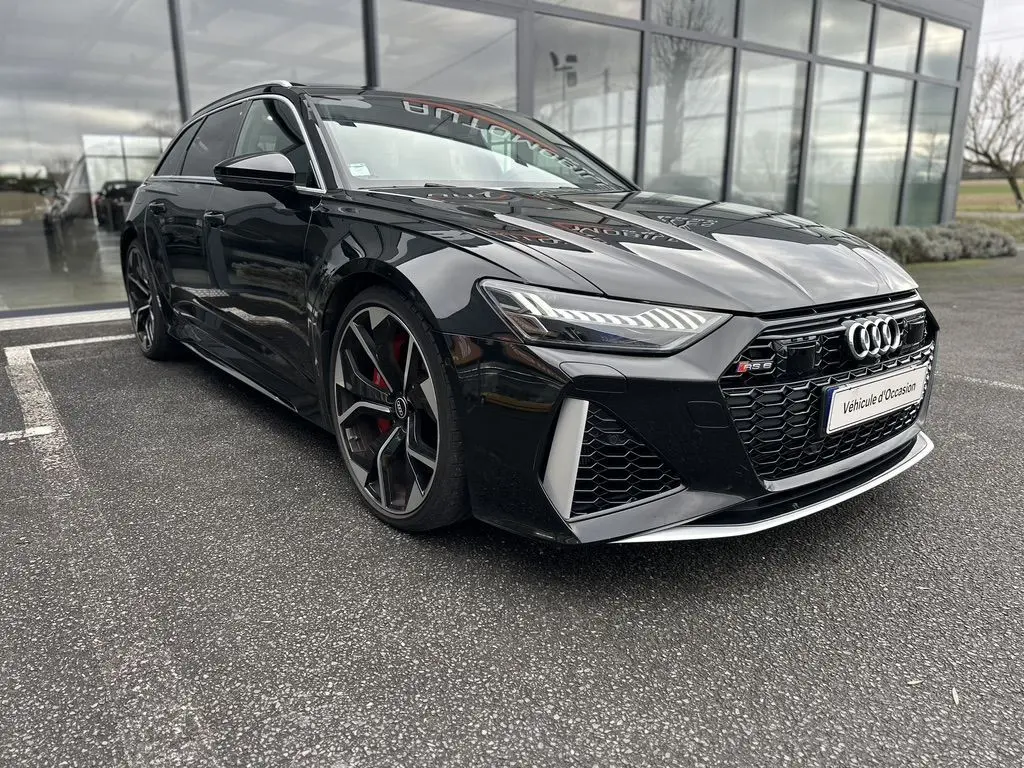 Audi RS6 Avant noire vue en 3/4 avant gauche, avec calandre noire et jantes sport à cinq branches doubles.