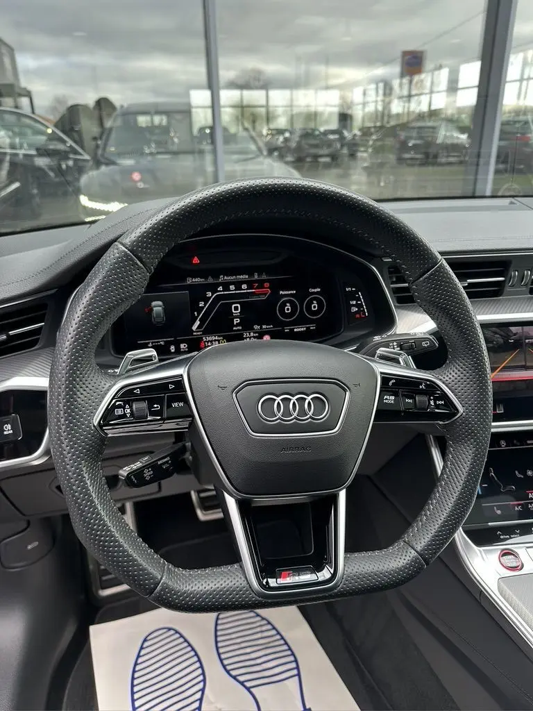 Volant perforé noir de l'Audi RS6 Avant 2021 avec affichage numérique et commandes intégrées vues de face depuis le poste de conduite.