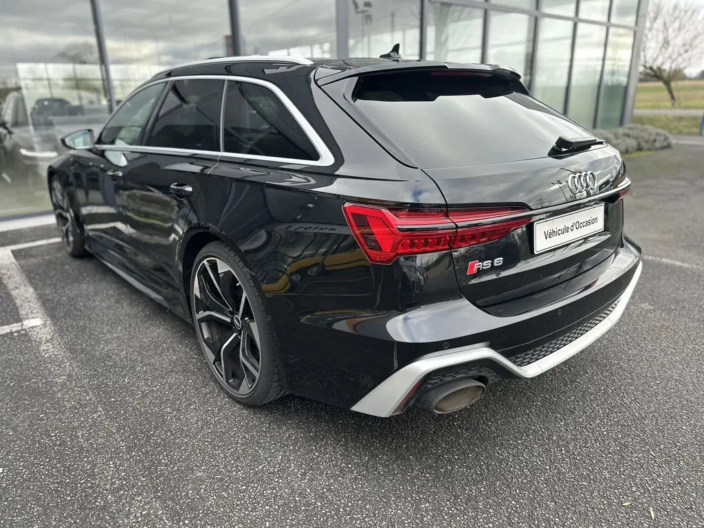 Audi RS6 Avant noire vue en 3/4 arrière droit, mettant en valeur ses feux LED et ses jantes sportives distinctives.