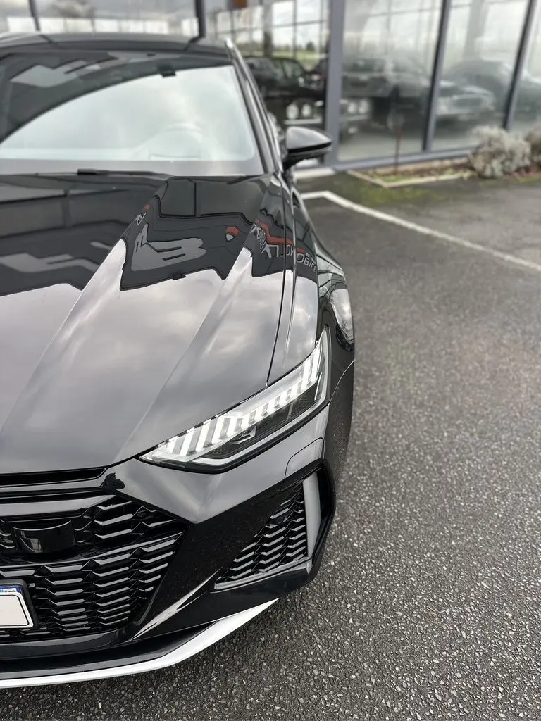Vue rapprochée 3/4 avant droit de l'Audi RS6 Avant noire avec phares LED et calandre sportive.