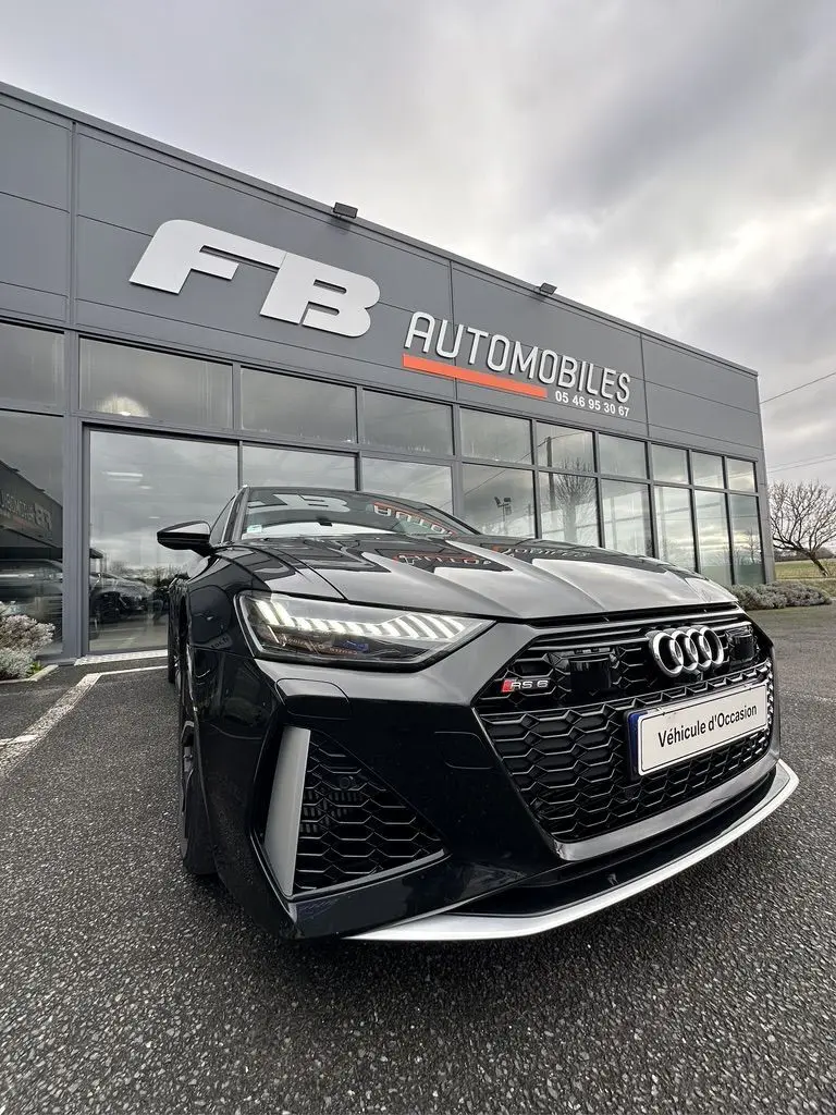 Audi RS6 Avant noire vue en 3/4 avant droit, mettant en valeur sa calandre hexagonale et ses phares LED distinctifs.